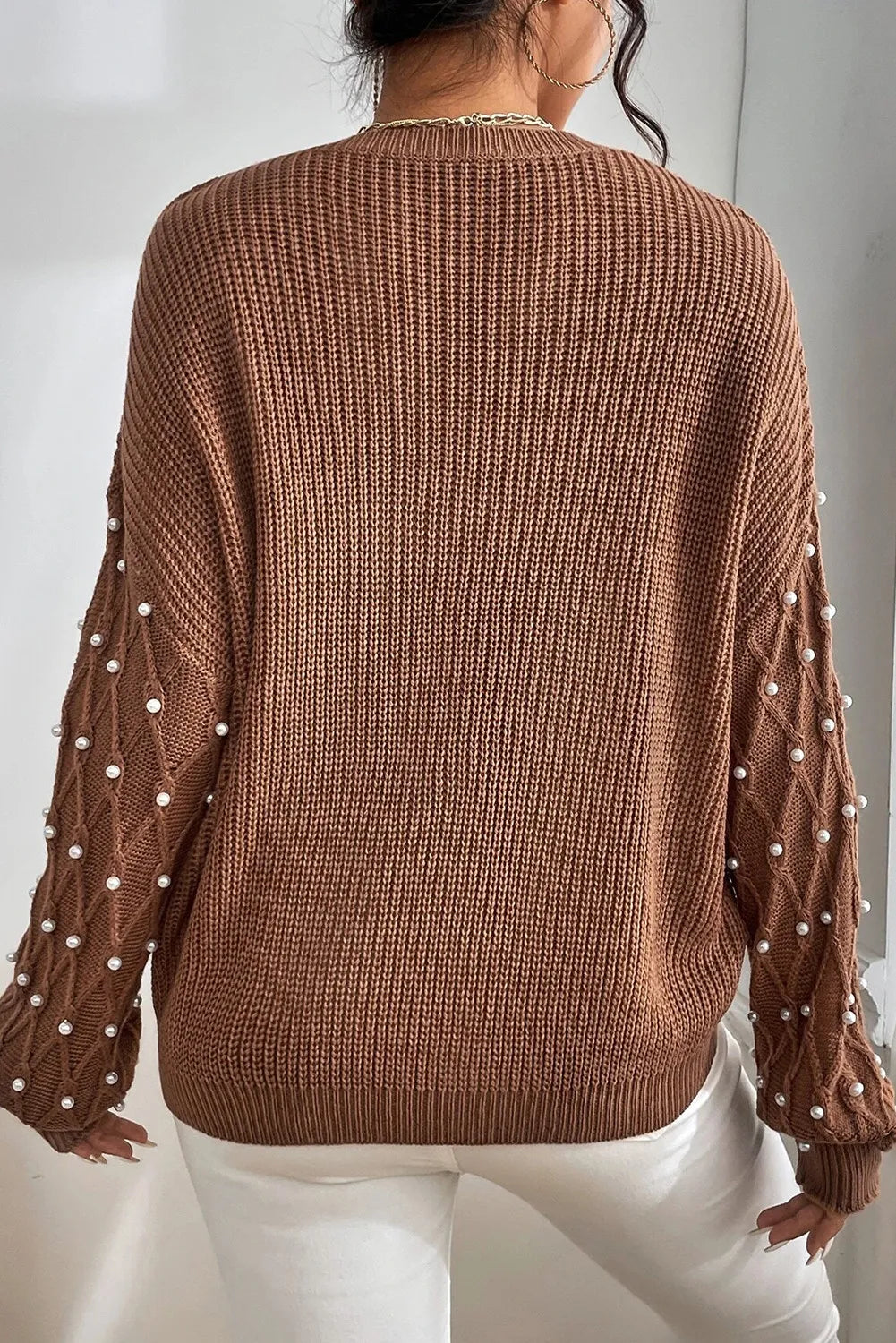 Brown cable knit sweater with pearl embellished sleeves and diamond pattern detail.