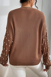Brown cable knit sweater with pearl embellished sleeves and diamond pattern detail.