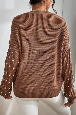 Brown cable knit sweater with pearl embellished sleeves and diamond pattern detail.