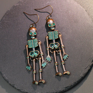 Skeleton silhouette drop earrings with teal accents and antique bronze finish