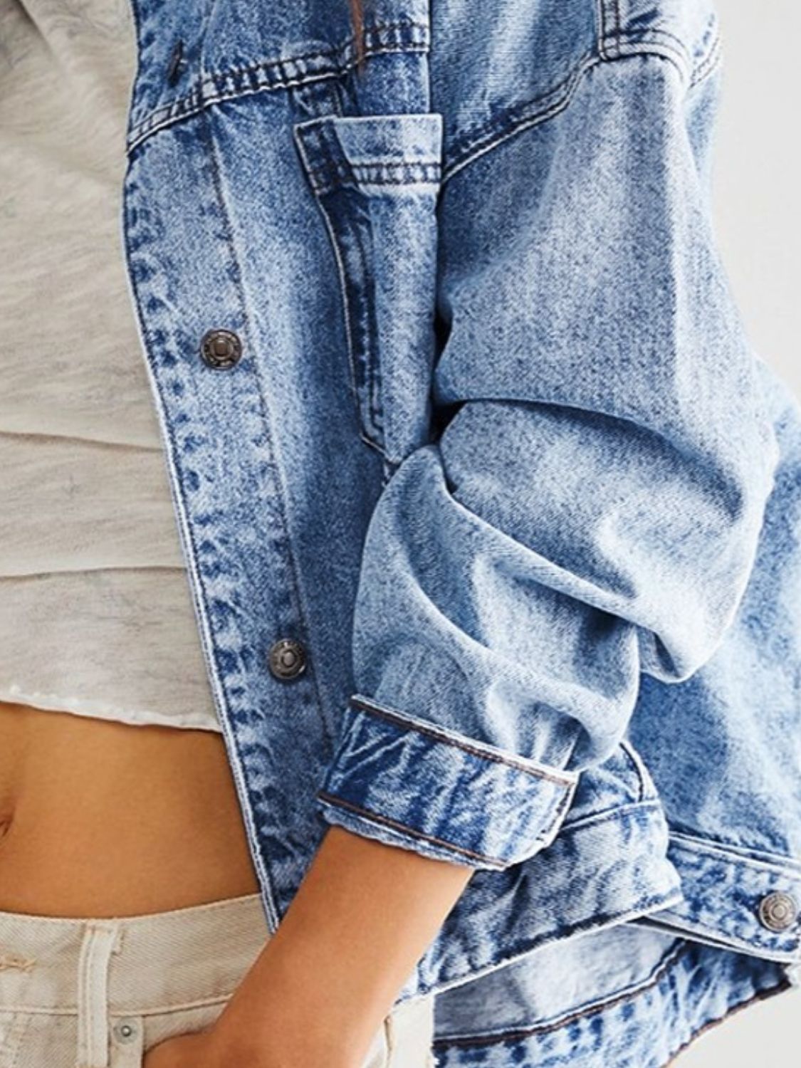 Oversized denim trucker jacket in light blue wash with button details and folded cuffs.