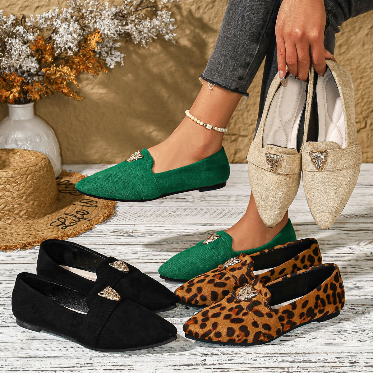 Point toe slip-on flats in green, black, apricot, and animal print with gold lion embellishment.