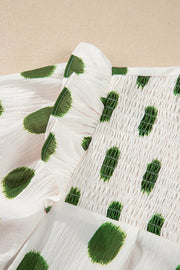 Textured polka dot blouse in matcha green with smocked yoke and ruffled detail.