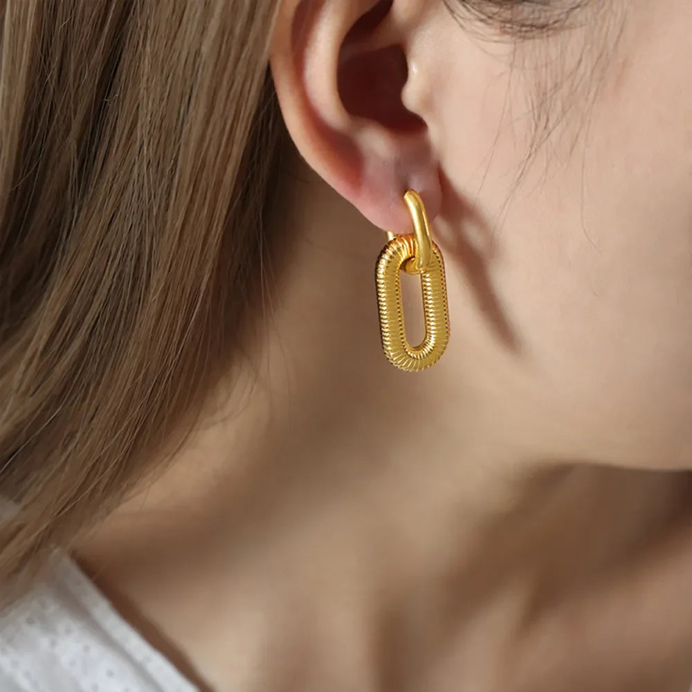 Gold textured oval link earrings with a ribbed surface detail.