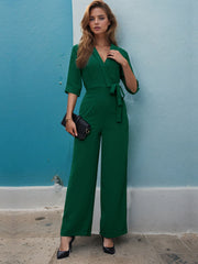 Dark green tailored wrap-front palazzo jumpsuit with tie waist and 3/4 sleeves.