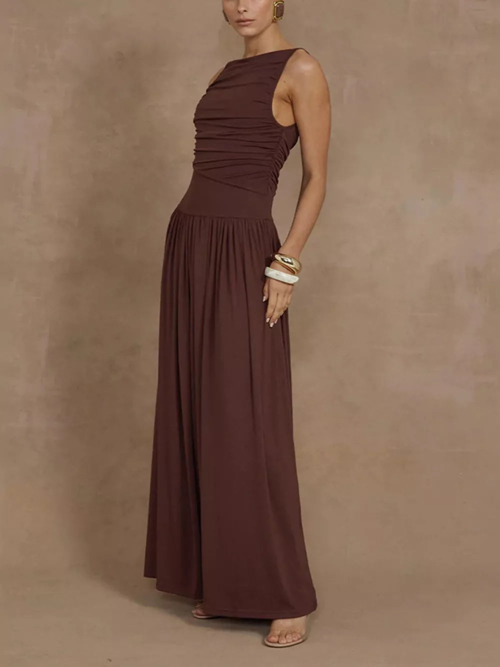 Brown ruched maxi dress with asymmetric neckline and flowing skirt.