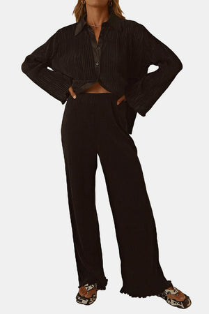 Black pleated shirt and wide-leg trousers set with bell sleeves and a collared neckline.
