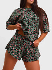 Vibrant leopard print lounge set with green and pink pattern, featuring a short-sleeve top and ruffled shorts.
