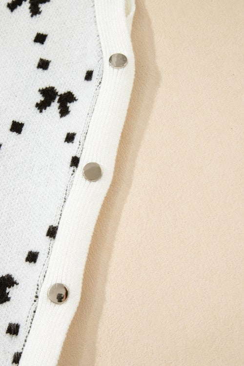 White knit tank sweater with black diamond bow pattern and silver snap closures.