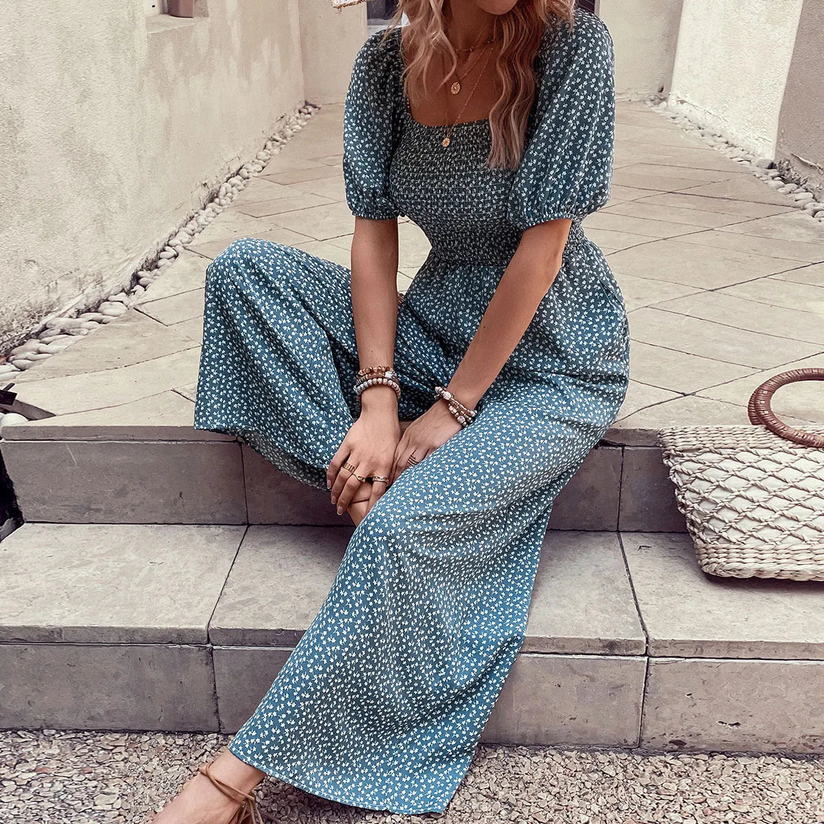 Smocked bodice floral wide-leg jumpsuit in dark green with puff sleeves and square neckline.