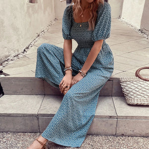 Smocked bodice floral wide-leg jumpsuit in dark green with puff sleeves and square neckline.