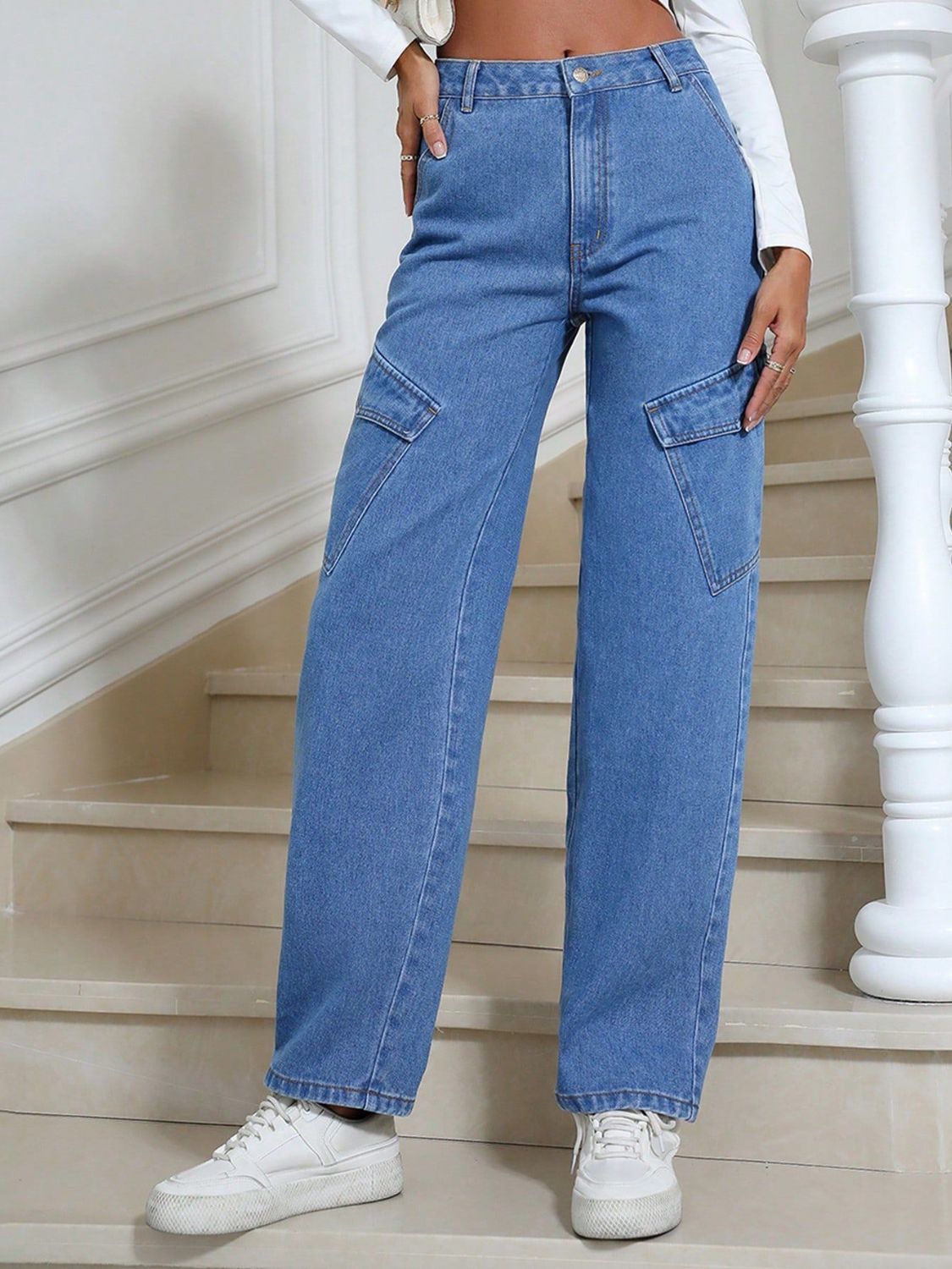 Medium wash denim cargo pants with angled buttoned pockets and straight legs.