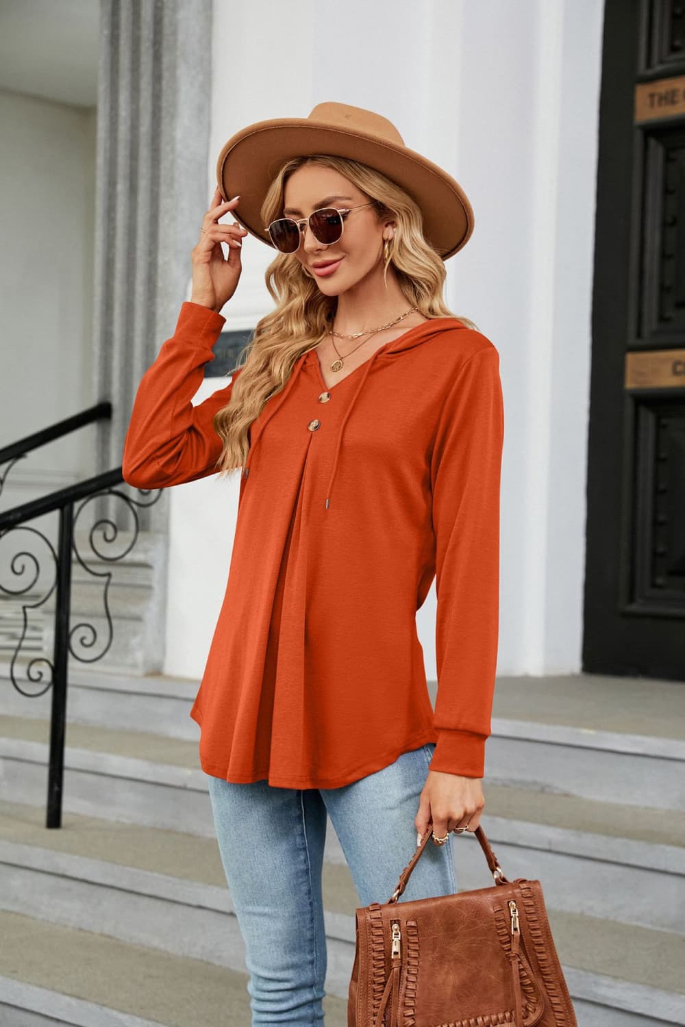 Orange hooded henley top with button detail and pleats.
