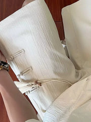 Beige chino shorts with drawstring, tassels, and knot button details.