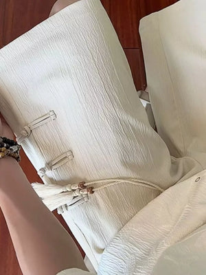 Beige chino shorts with drawstring, tassels, and knot button details.