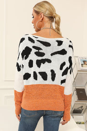 Cow print knit sweater with boat neck and orange band detail.