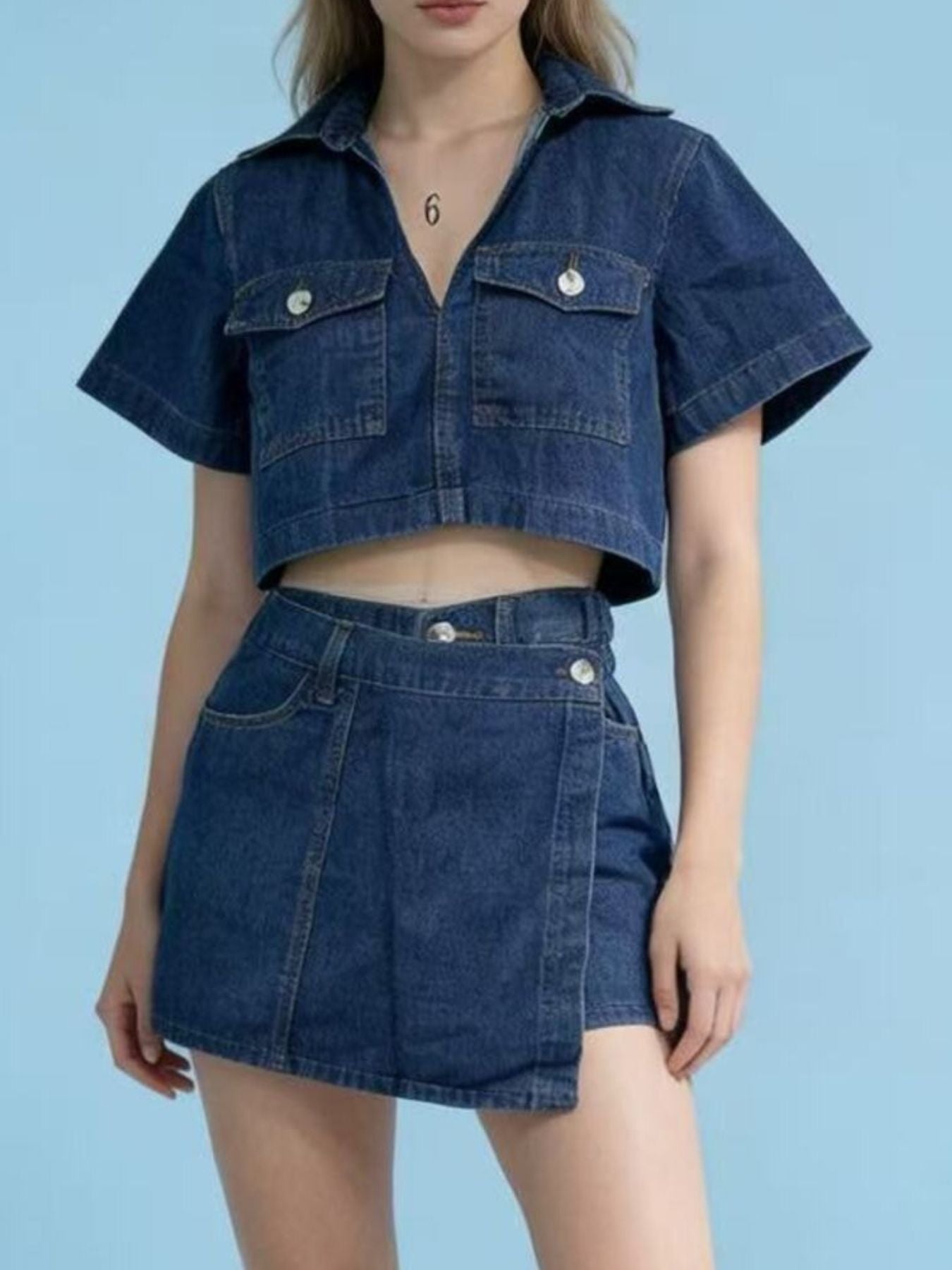 Medium wash denim cropped button-down top and mini skort set with short sleeves and two chest pockets.
