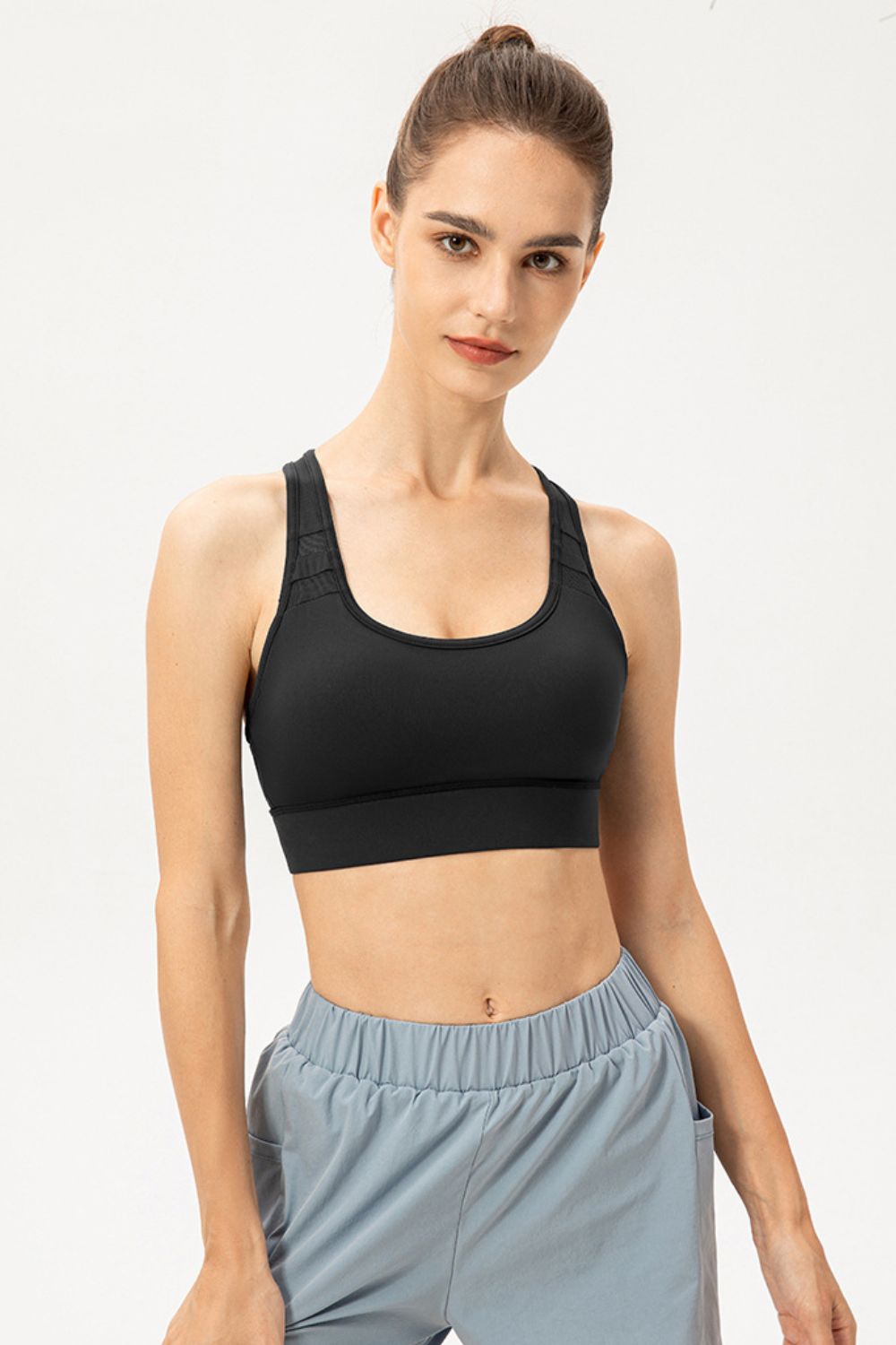 Black sports bra with mesh inset detail on straps and scoop neckline.