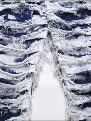 Distressed shredded denim jeans in medium wash with artistic blue tie-dye effect and frayed details.