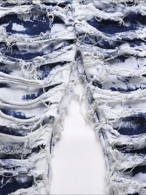 Distressed shredded denim jeans in medium wash with artistic blue tie-dye effect and frayed details.