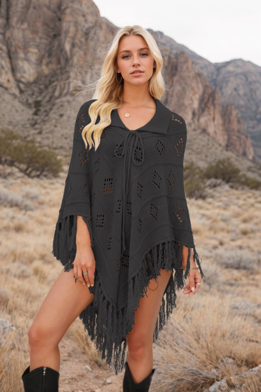 Black knit poncho with geometric pattern, fringe, and tie neck, styled with a collar.