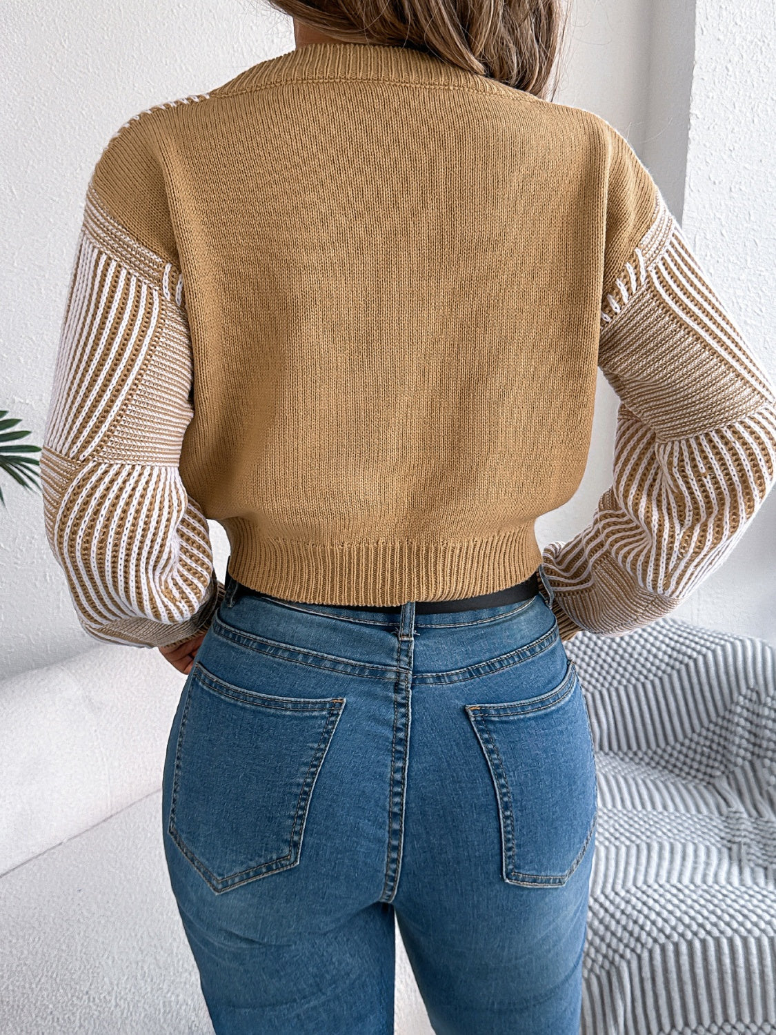 Tan cropped knit sweater with geometric stripe sleeves and V-neck.