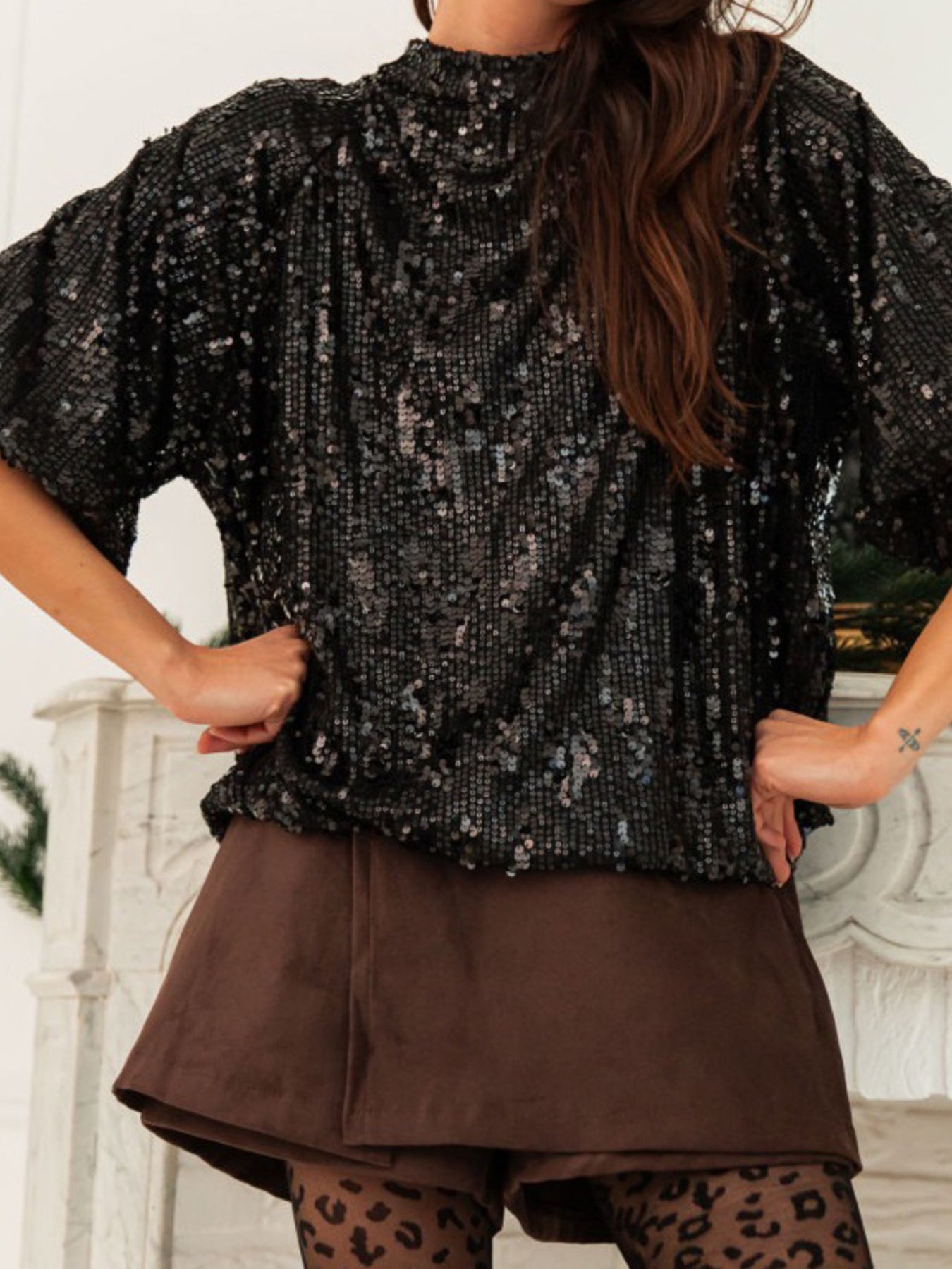 Black sequin tie-back blouse with mock neck and short sleeves, styled with brown shorts.