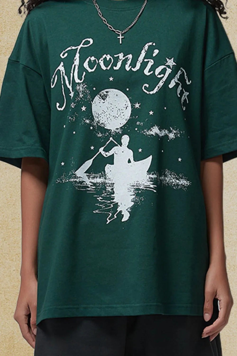 Dark green oversized tee with a white graphic of a person in a canoe under a moon and stars.