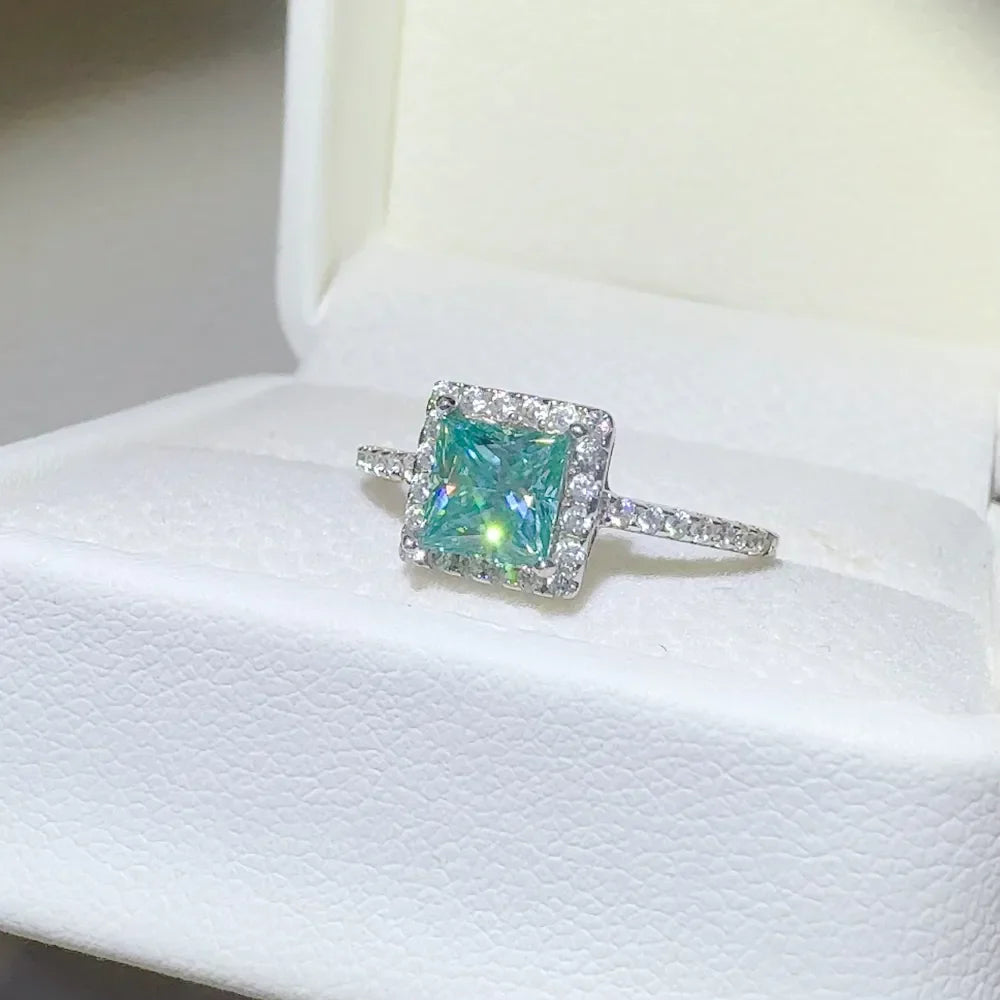 Silver ring with square teal moissanite center stone and diamond halo.