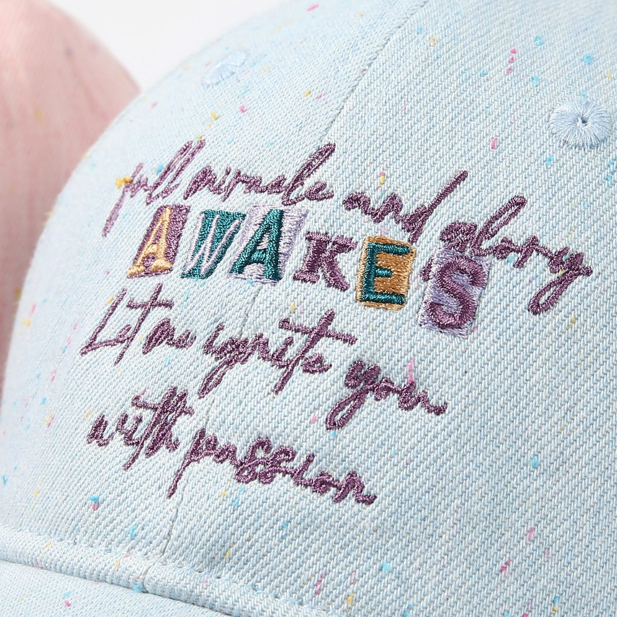 Light blue embroidered text baseball cap with confetti speckles and curved brim.