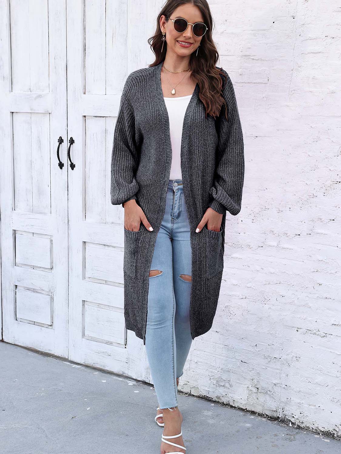 Charcoal ribbed knit maxi cardigan with pockets and balloon sleeves, worn open over a white top and ripped jeans.