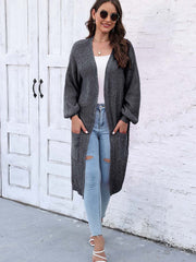 Charcoal ribbed knit maxi cardigan with pockets and balloon sleeves, worn open over a white top and ripped jeans.