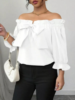 White off-the-shoulder blouse with ruffled neckline and large bow detail.