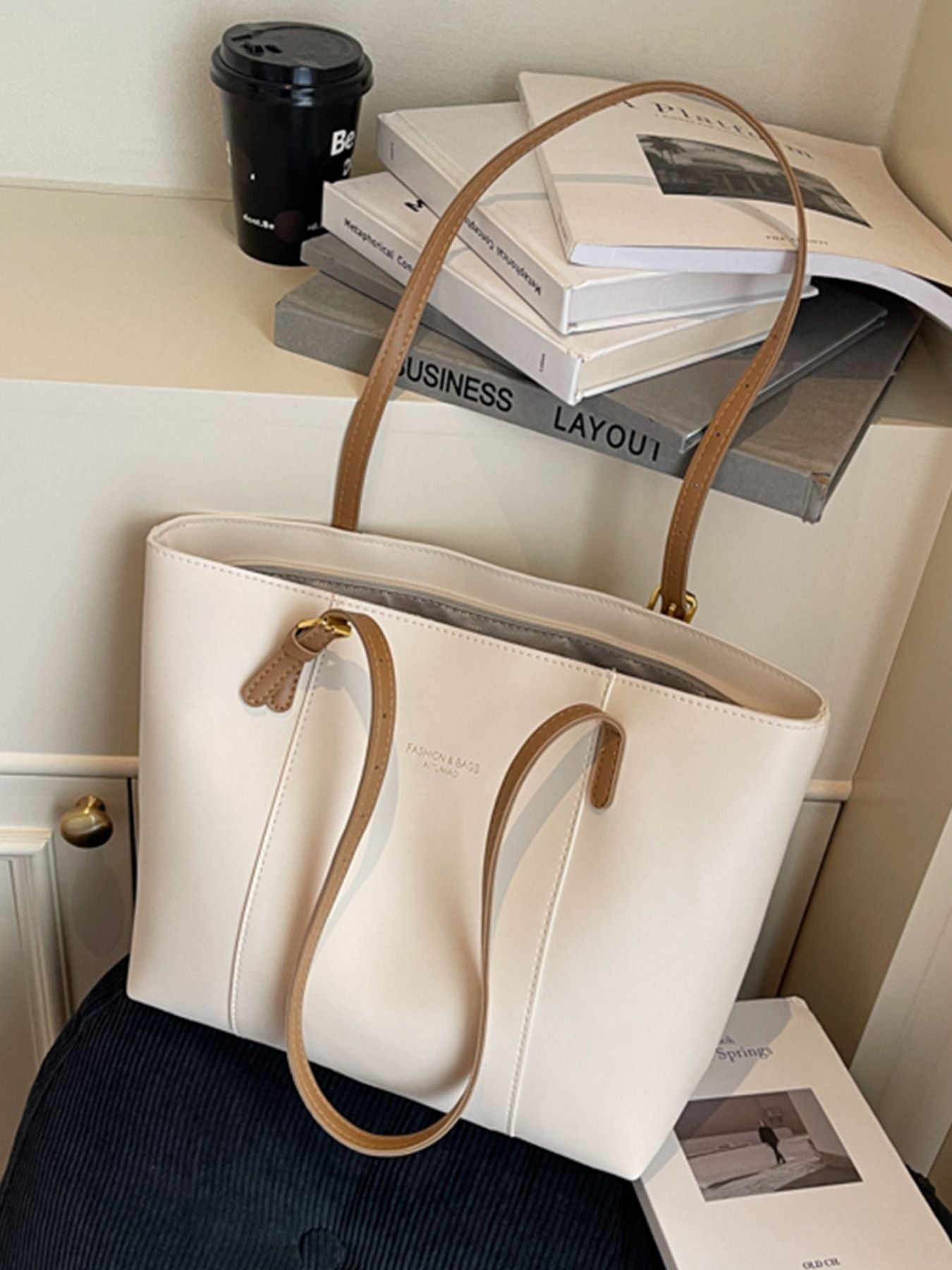 White structured PU leather tote bag with brown handles and subtle embossed logo.