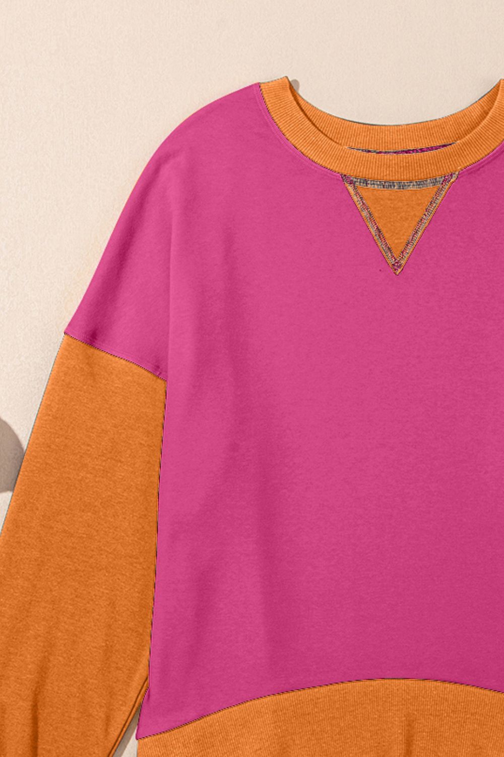 Chic Contrast Crewneck Sweatshirt in hot pink and tan with orange accents and a v-stitch detail.