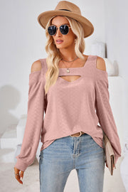 Blush pink textured blouse with cutout shoulder and neckline detail.