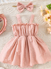 Pink floral embossed baby one-piece dress with ruffled neckline and matching bow headband.