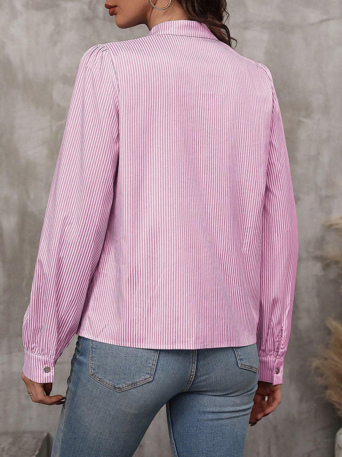 Pink striped blouse with puffed sleeves and button cuffs, styled with jeans.