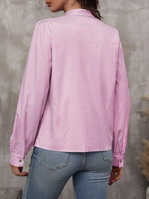 Pink striped blouse with puffed sleeves and button cuffs, styled with jeans.