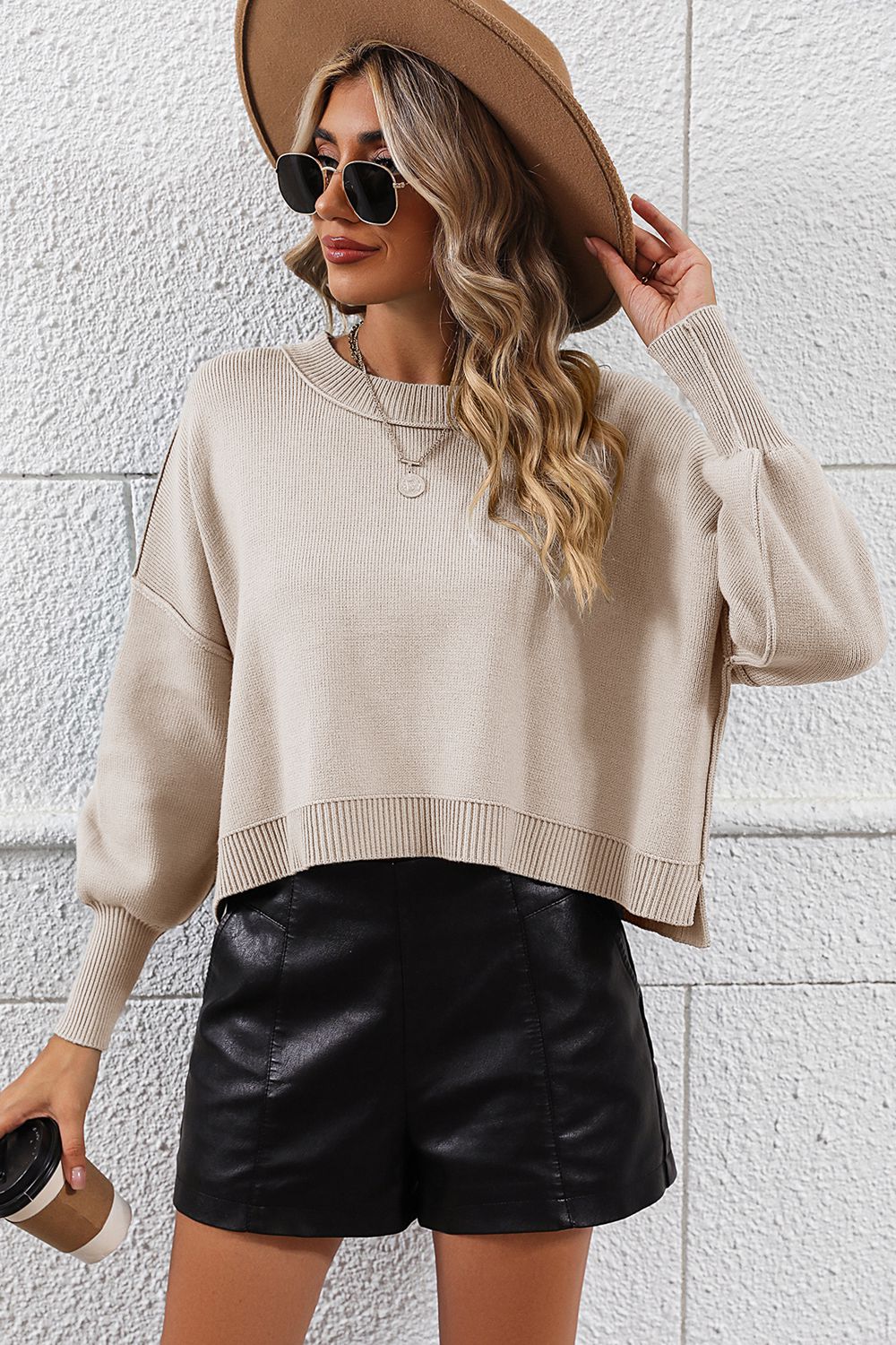 Beige cropped knit sweater with dolman sleeves and crew neck, styled with black shorts.