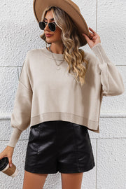 Beige cropped knit sweater with dolman sleeves and crew neck, styled with black shorts.