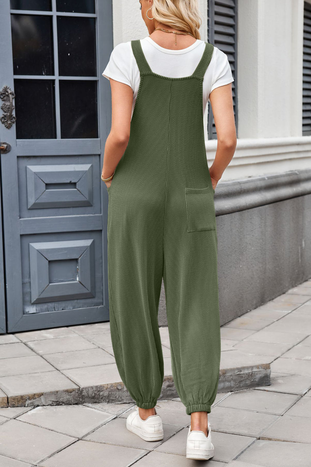 Olive green corduroy overalls with barrel leg and back pockets, worn with a white t-shirt.