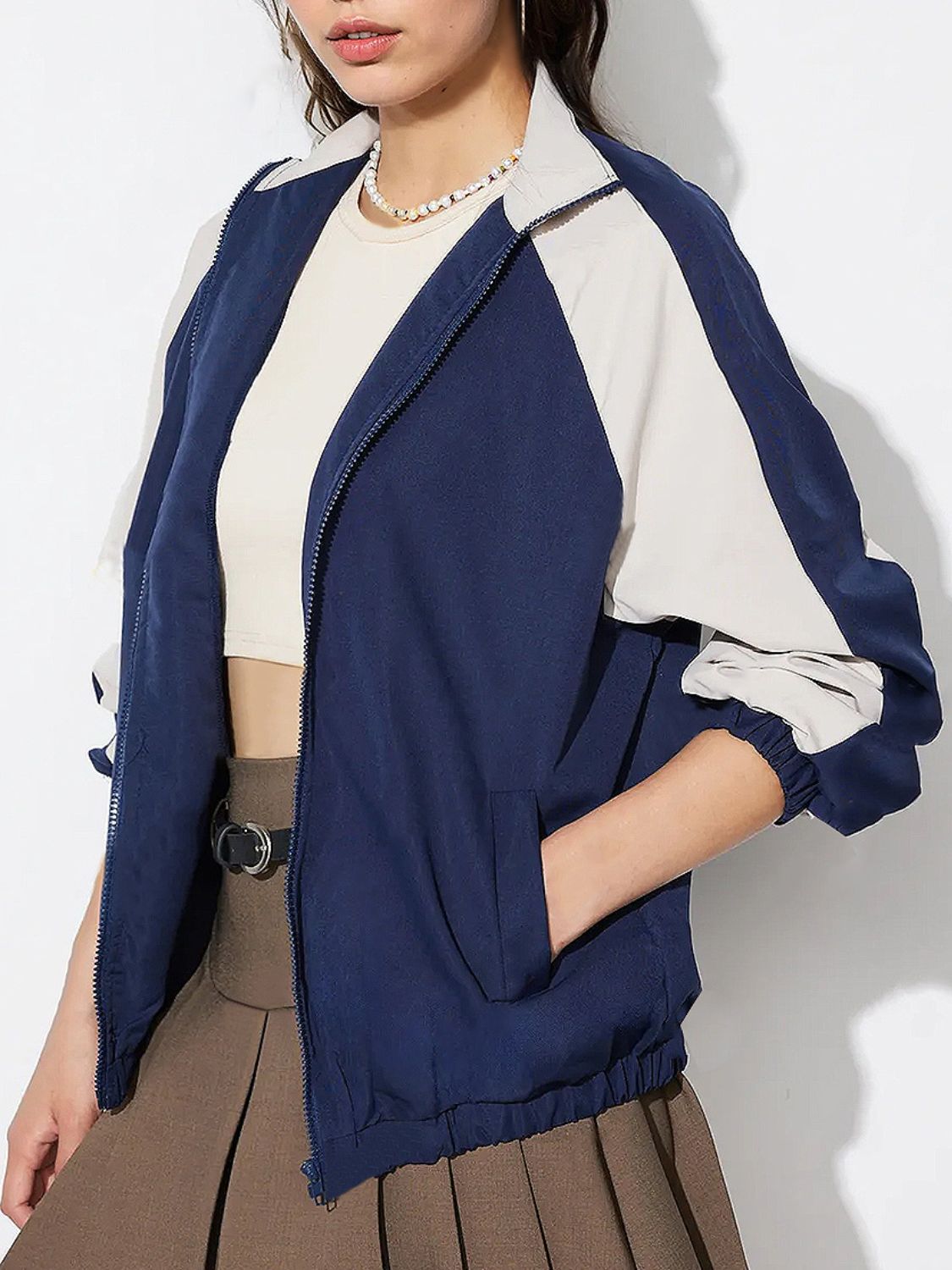 Colorblock raglan sleeve bomber jacket in dark blue and light beige with zip front and elastic cuffs.