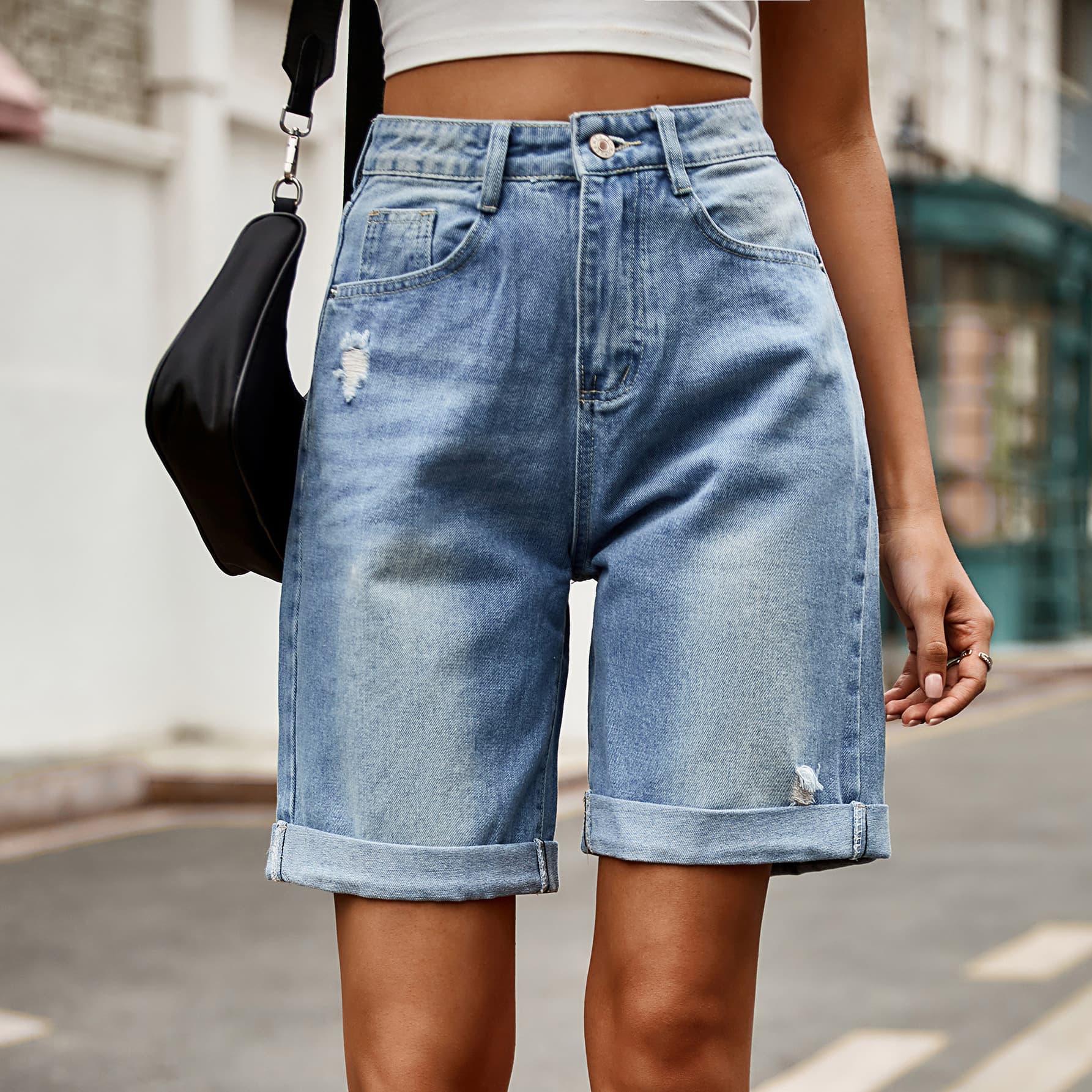 Medium wash denim boyfriend shorts with rolled hems and distressed details.
