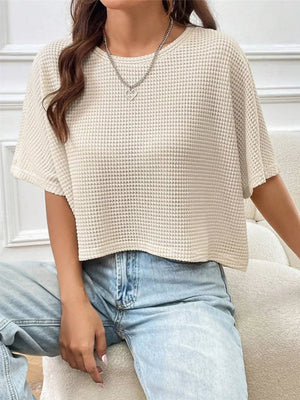 Apricot waffle-knit cropped t-shirt with crew neck and short sleeves, styled with jeans.