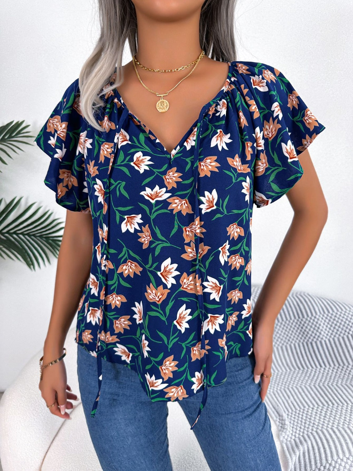 Dark blue floral ruffle sleeve tie-neck blouse made of 100% polyester.