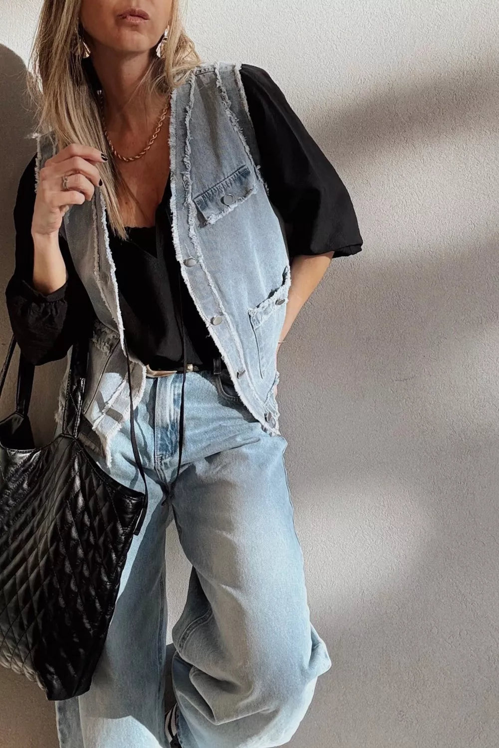 Light wash denim vest with frayed edges and chest pockets, button-down closure.