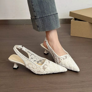 White lace slingback kitten heels with floral pattern and pointed toe.