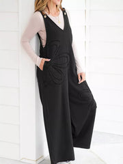 Black cotton wide-leg maternity romper with floral appliqué and button straps.
