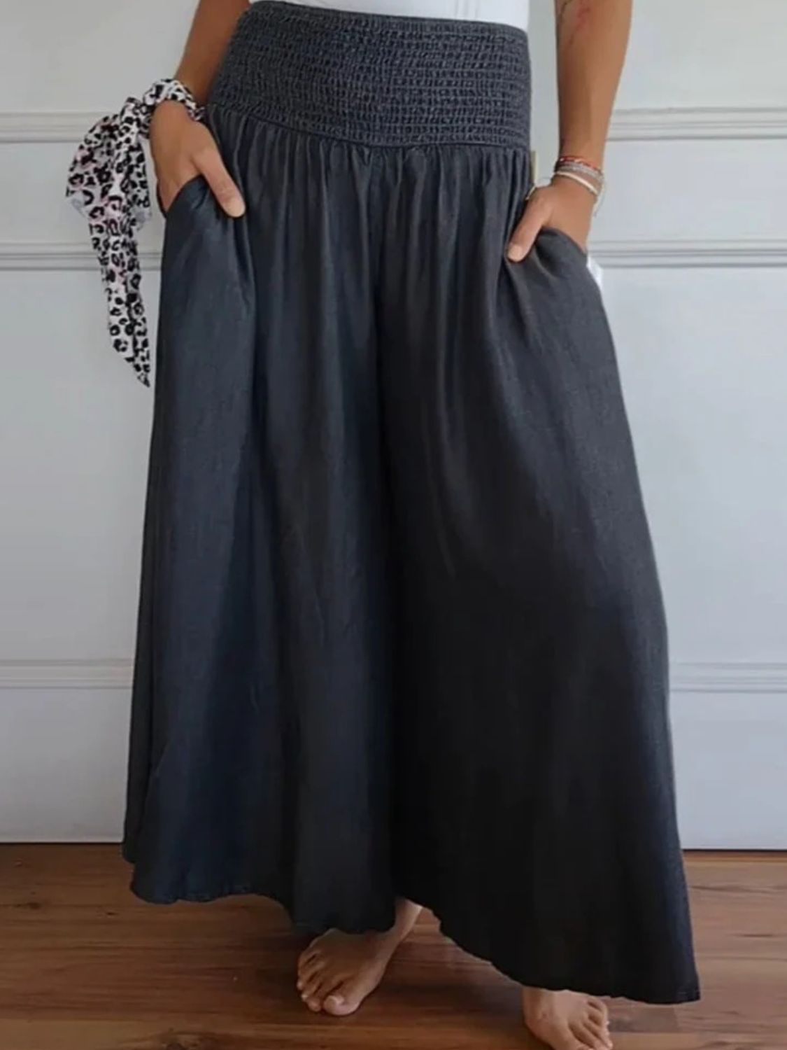 Smocked waistline flow trousers in black with pockets and a wide leg.
